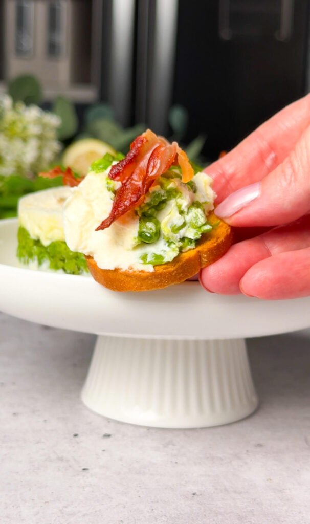 crostini topped with ricotta pea timbale and crispy prosciutto bite close up