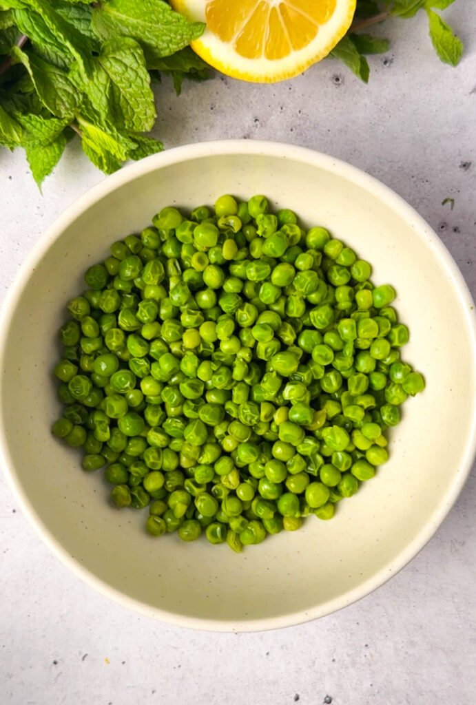 fresh green peas in bowl for ricotta pea timbale spring appetizer preparation