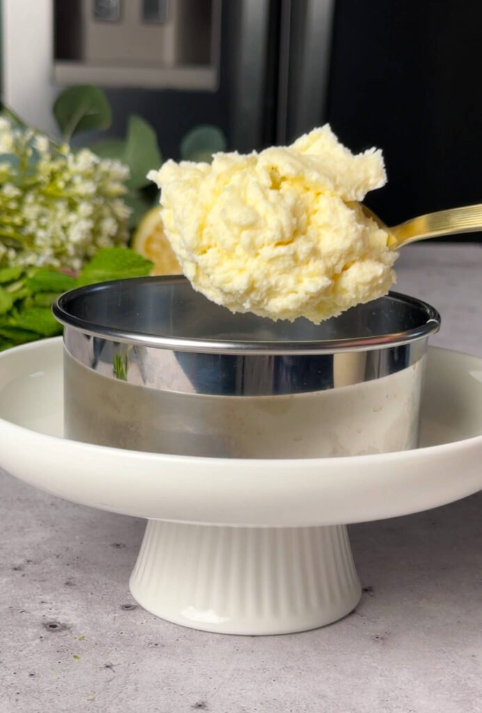 creamy ricotta layer being added into ring mold for ricotta pea timbale assembly