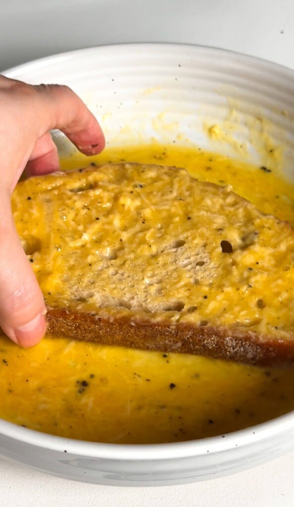 dipping sourdough bread into egg and parmesan mixture before frying