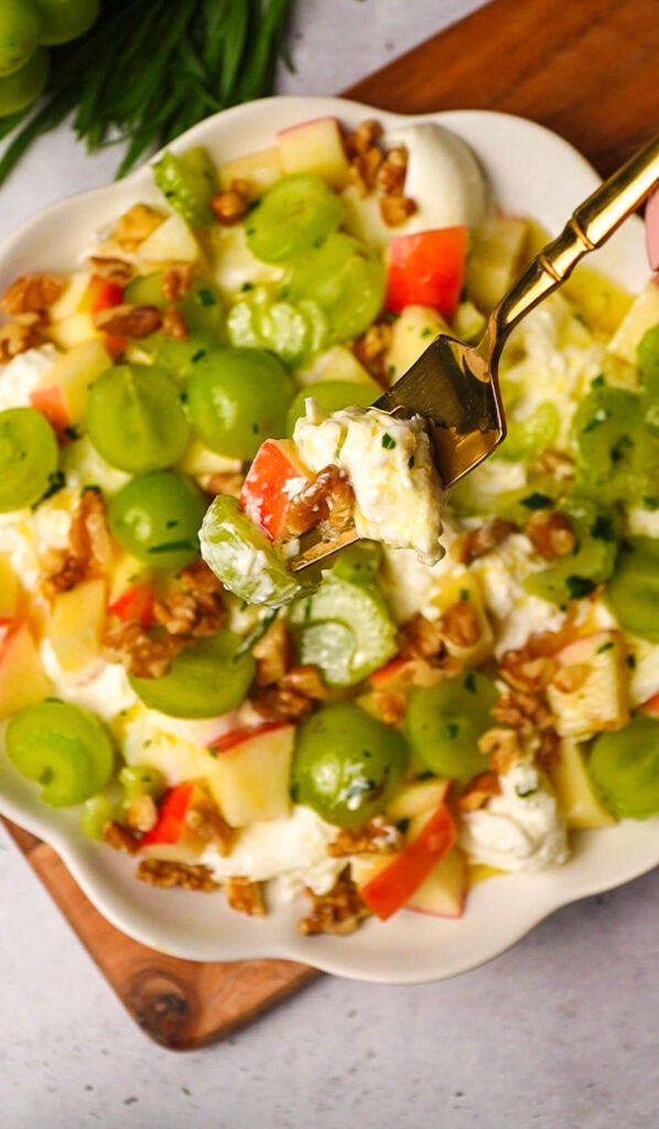 fork bite of waldorf salad with burrata, apple, grape and walnut with creamy texture