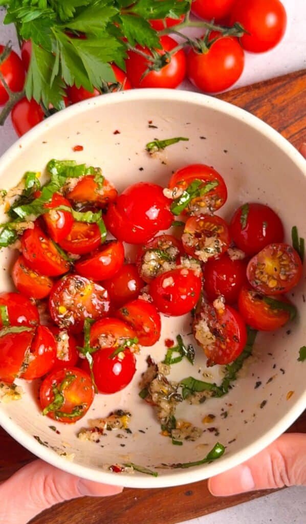 Cherry tomatoes tossed with fresh basil, garlic, and herbs in a ceramic bowl — bruschetta topping for baked cheese dip