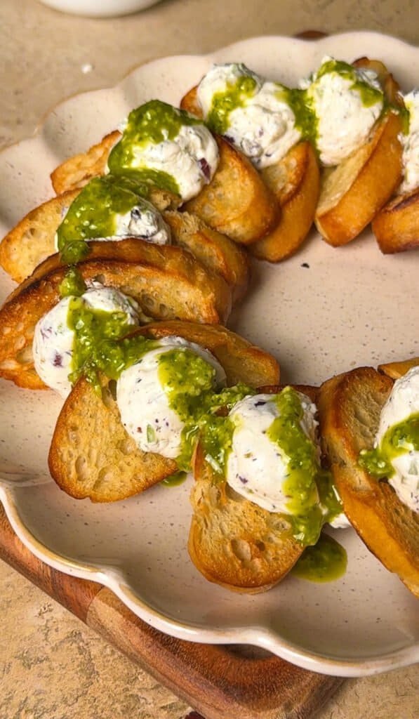 Mini potato skewers topped with herb cheese and drizzled with vibrant green sauce, perfect for appet.