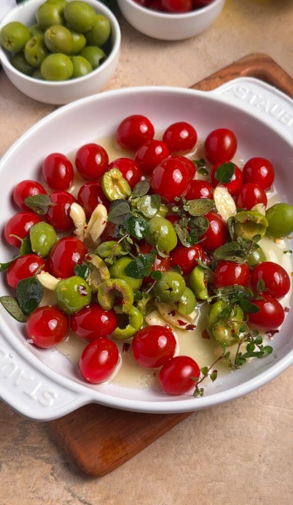 roasted tomato burrata ingredients with cherry tomatoes, olives, garlic and oregano in baking dish