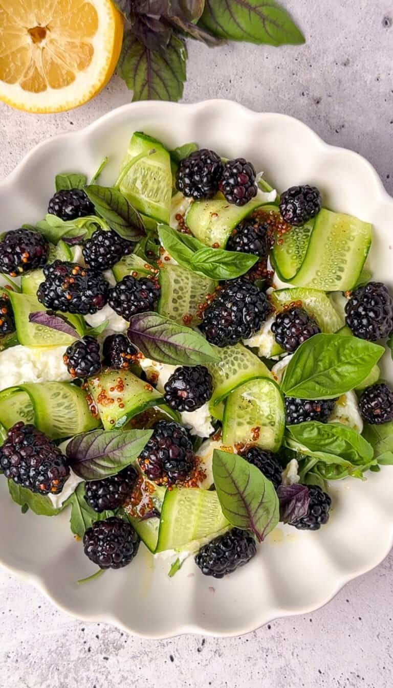 Overhead shot of blackberry burrata salad with basil, cucumber ribbons, and honey Dijon dressing