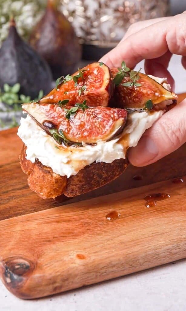 Close-up of a fig and goat cheese crostini with balsamic glaze and thyme