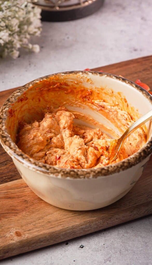 Harissa cream cheese being stirred together in a bowl for sardine toast