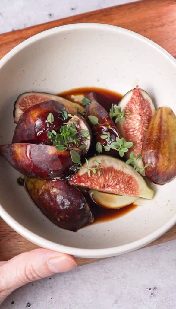 Quartered fresh figs marinating in balsamic and honey glaze with fresh thyme sprigs