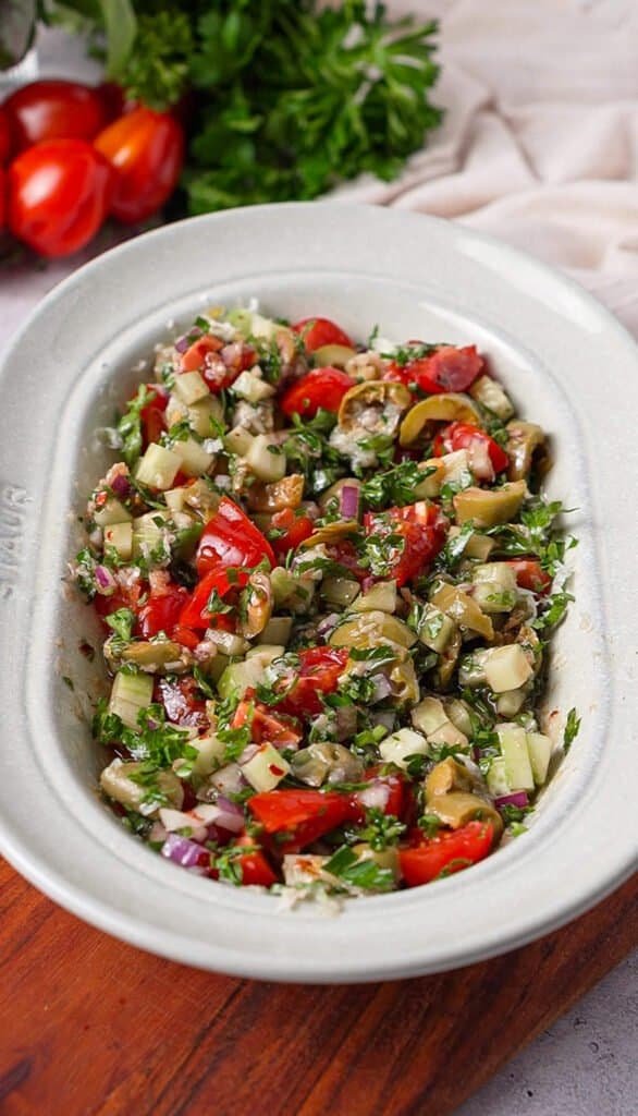 Mediterranean tomato dip with olives, cucumber, and parsley mixed together in a serving bowl