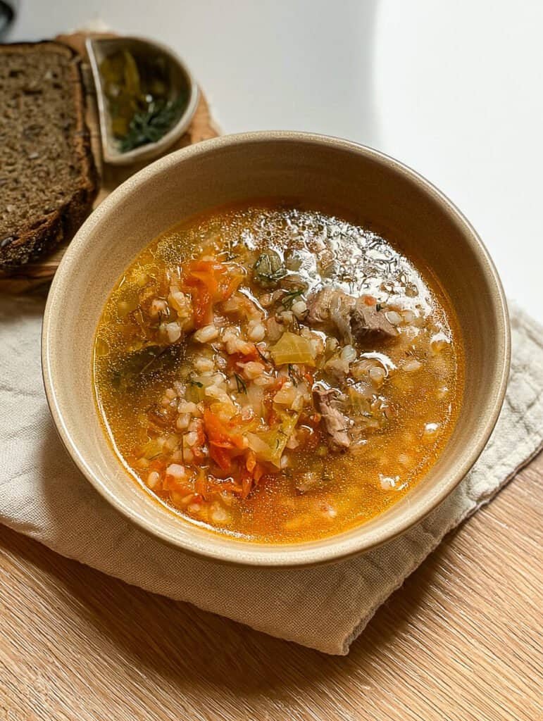 Overhead view of pickle soup recipe rassolnik served with rye bread and pickles