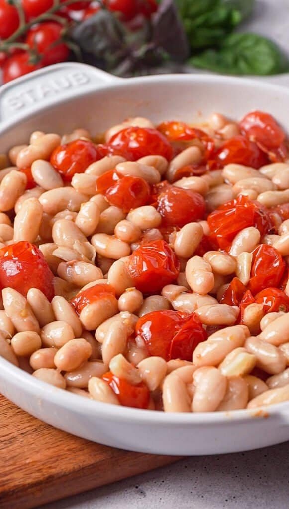 Roasted cherry tomatoes and great northern beans in a white baking dish