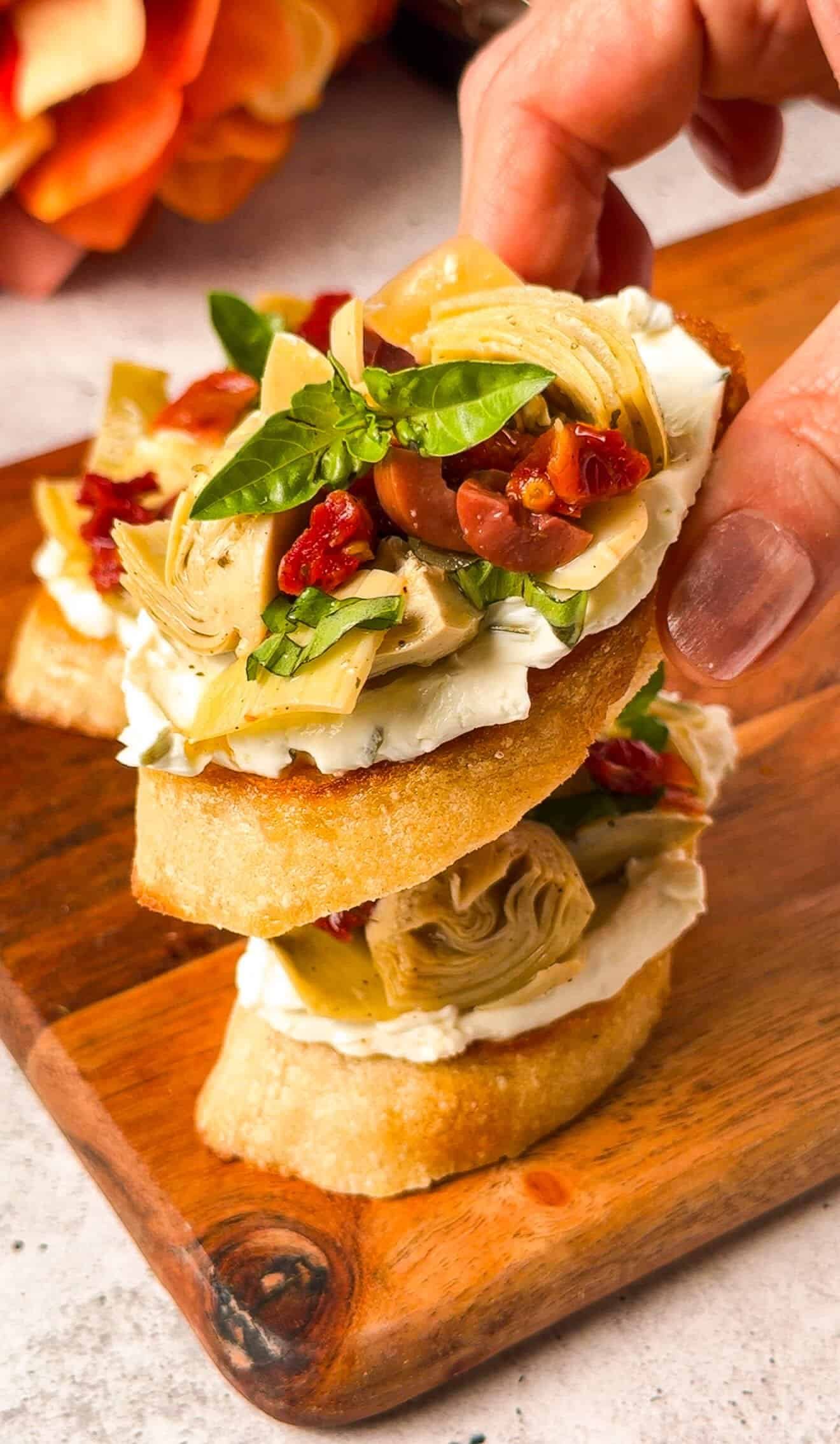 Close-up of stacked artichoke crostini showing labneh, artichoke, and sun-dried tomato layers