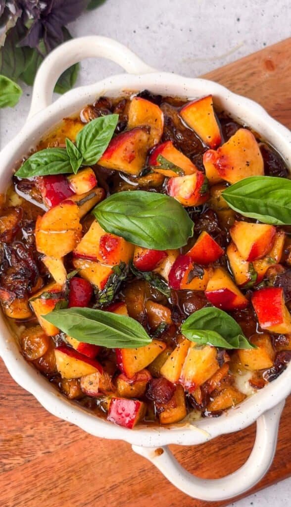 Overhead view of baked peach bacon dip topped with fresh basil leaves