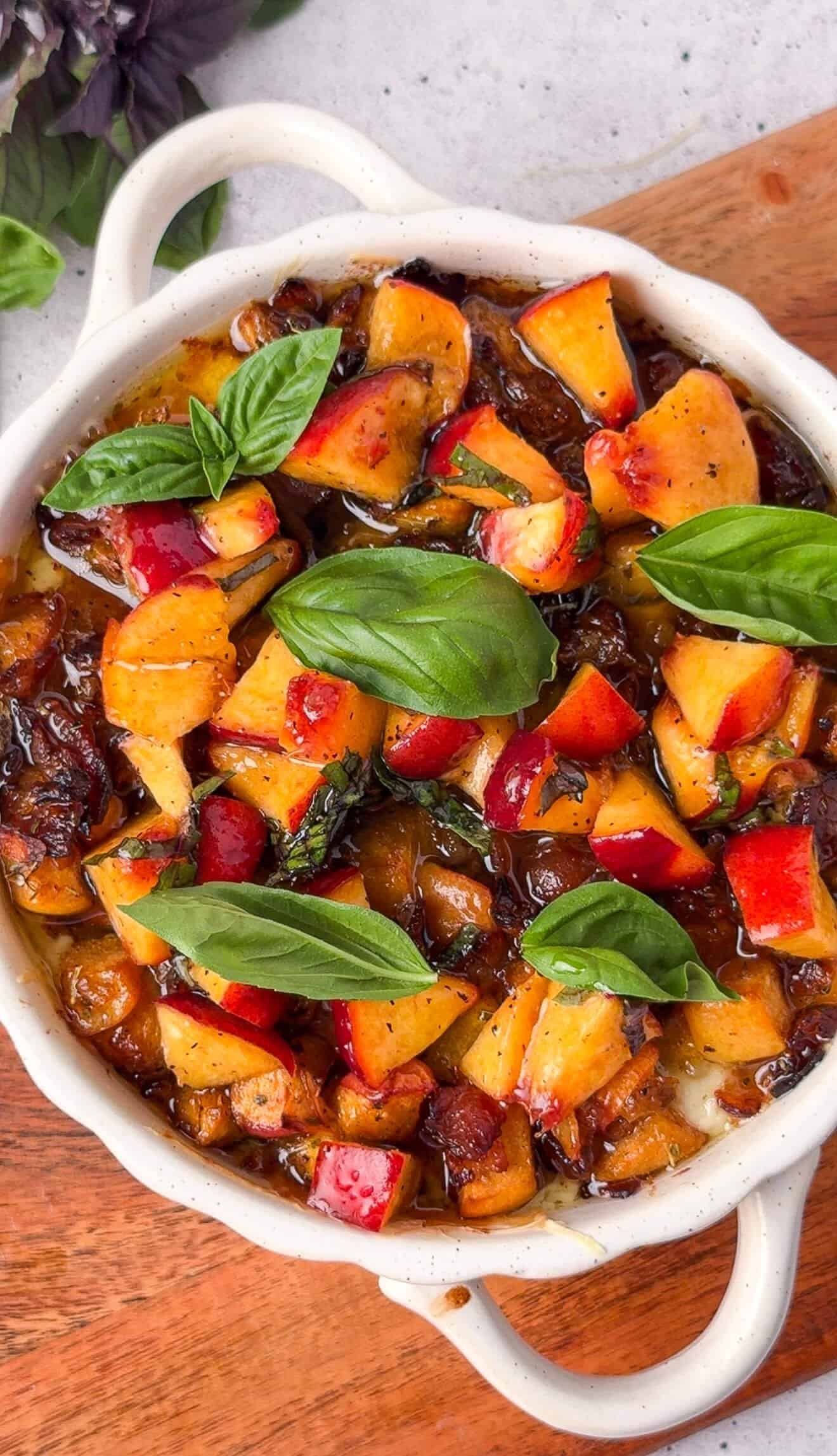 Overhead view of baked peach bacon dip topped with fresh basil leaves