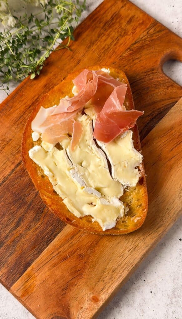 Sourdough toast layered with sliced brie and folded prosciutto before adding roasted figs
