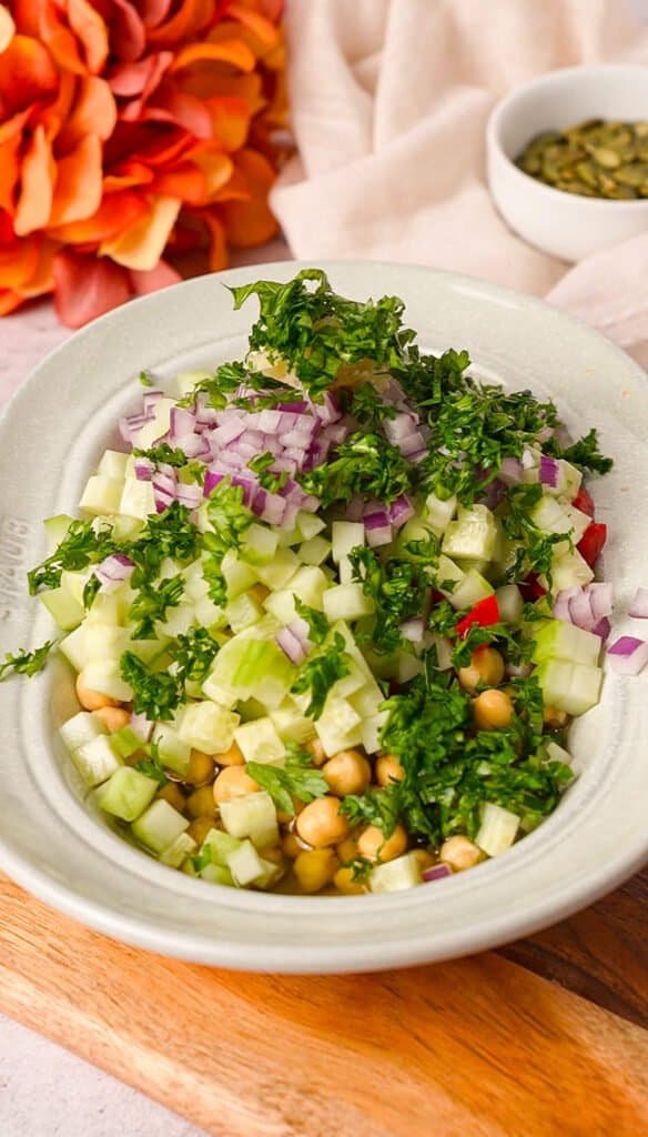 chopped cucumber, red onion, roasted red pepper, and fresh herbs in a bowl with chickpeas