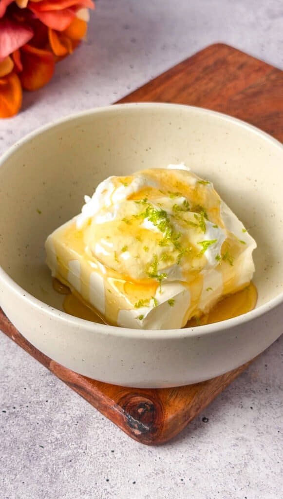 Cream cheese in a bowl topped with honey and lime zest before mixing for pear cheesecake filling