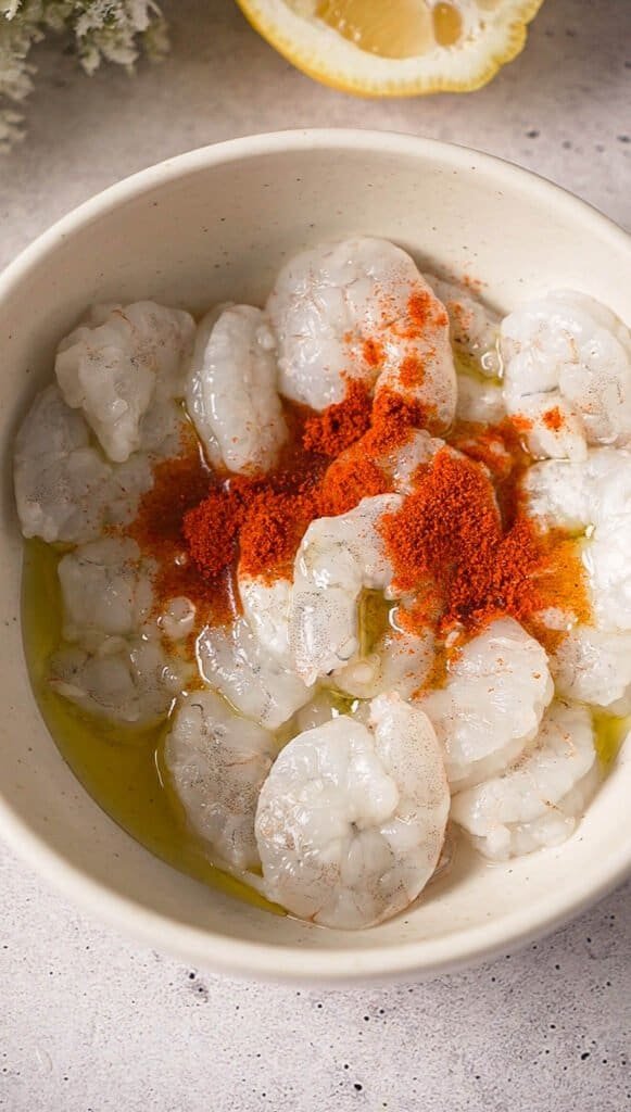 Raw shrimp marinating in olive oil with smoked paprika before searing