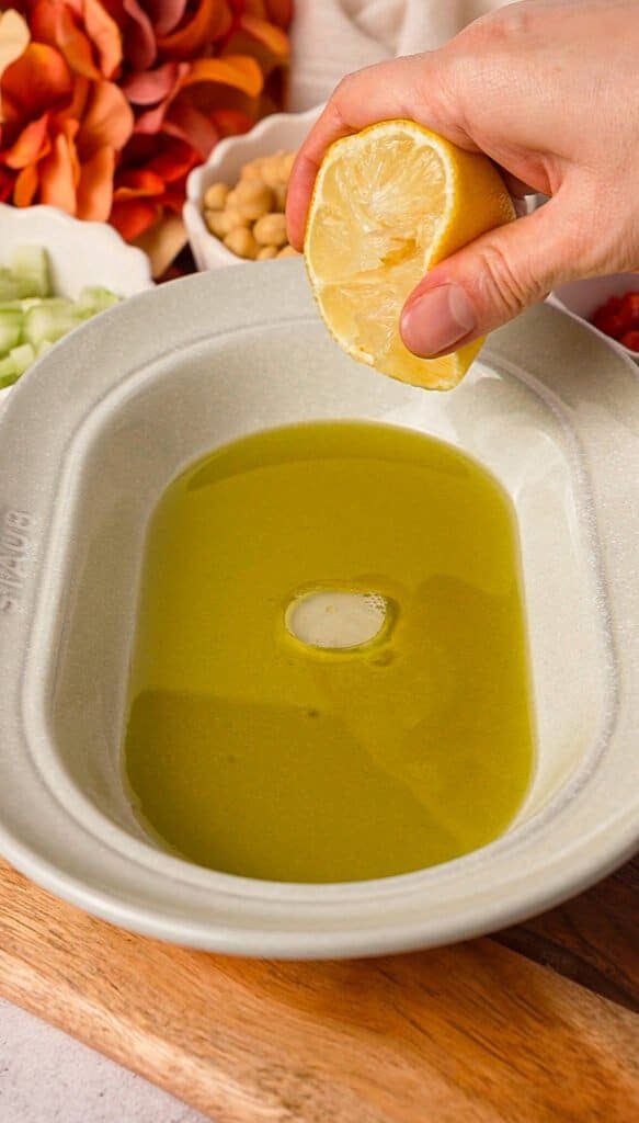 fresh lemon being squeezed into olive oil dressing for chickpea salad