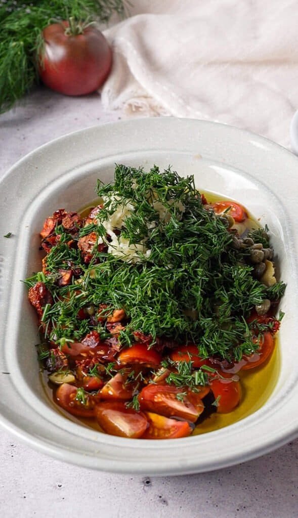 Fresh dill and parsley added on top of tomatoes and olives before mixing