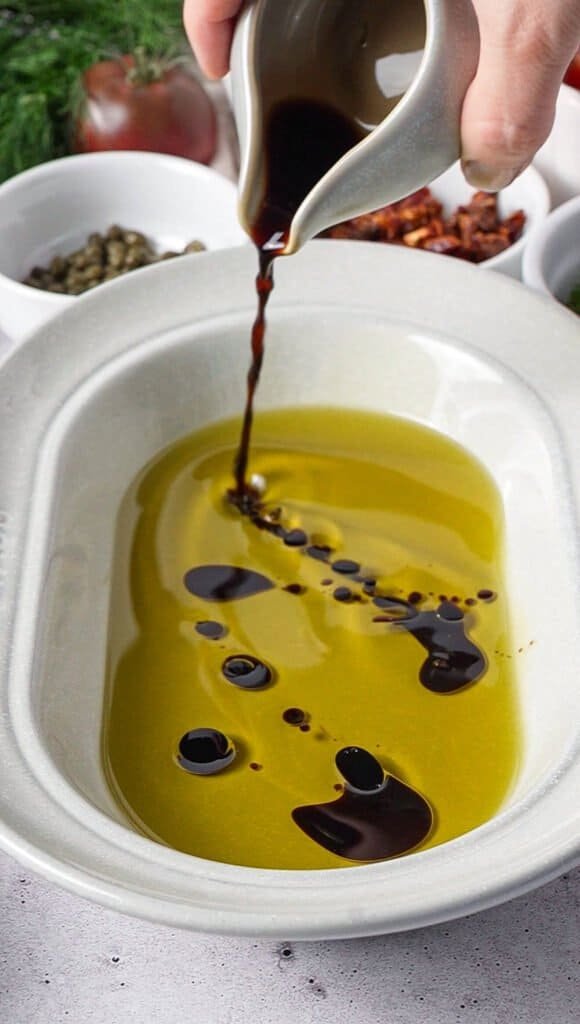 Balsamic vinegar being poured into olive oil for feta dip marinade