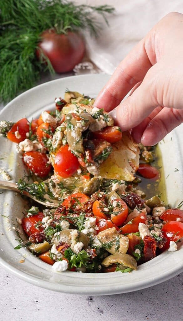Close-up of bread piled with marinated feta, olives, and sun-dried tomatoes