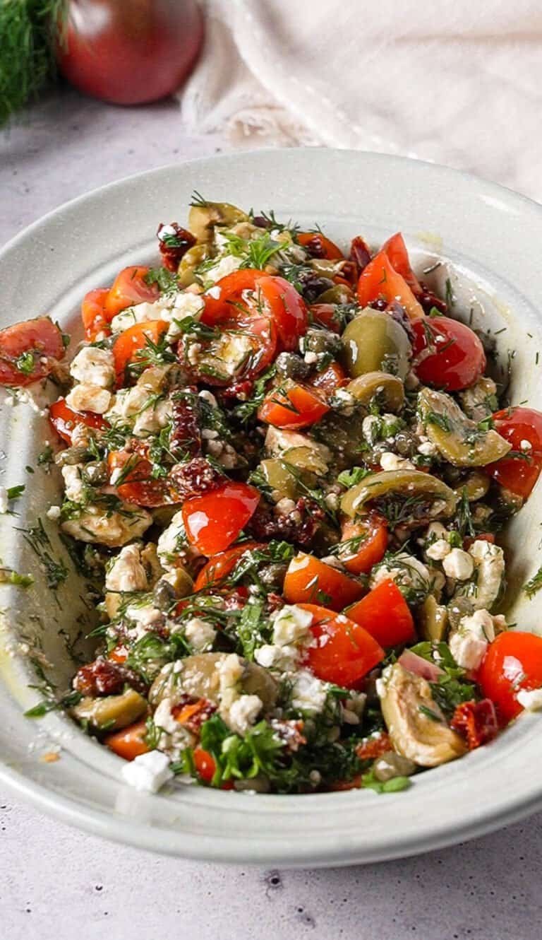 Overhead view of marinated feta dip with olives, capers, and sun-dried tomatoes