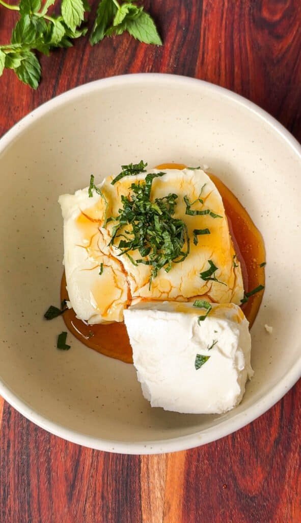 Cream cheese and goat cheese topped with honey and chopped mint before mixing