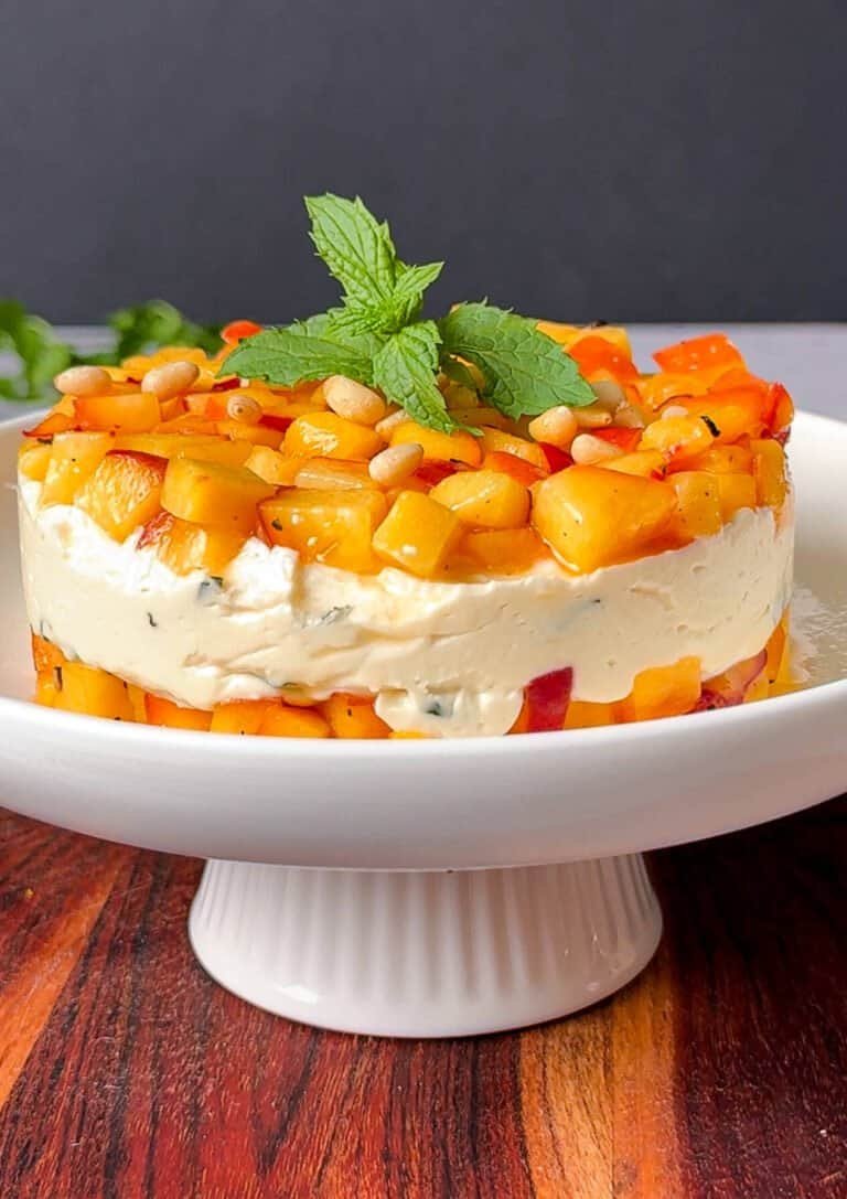 Peach, honey and goat cheese appetizer stack unmolded and garnished with pine nuts and mint