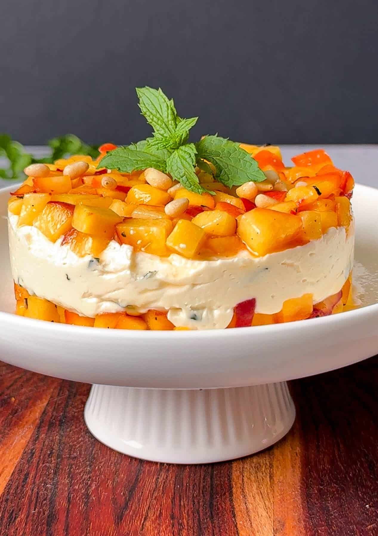 Peach, honey and goat cheese appetizer stack unmolded and garnished with pine nuts and mint