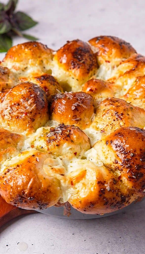 golden baked pesto pull apart bread in a skillet topped with parmesan and chili flakes