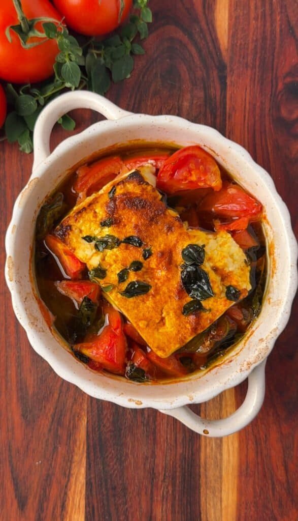 Baked feta with tomatoes and peppers fresh from the oven, cheese softened and browned