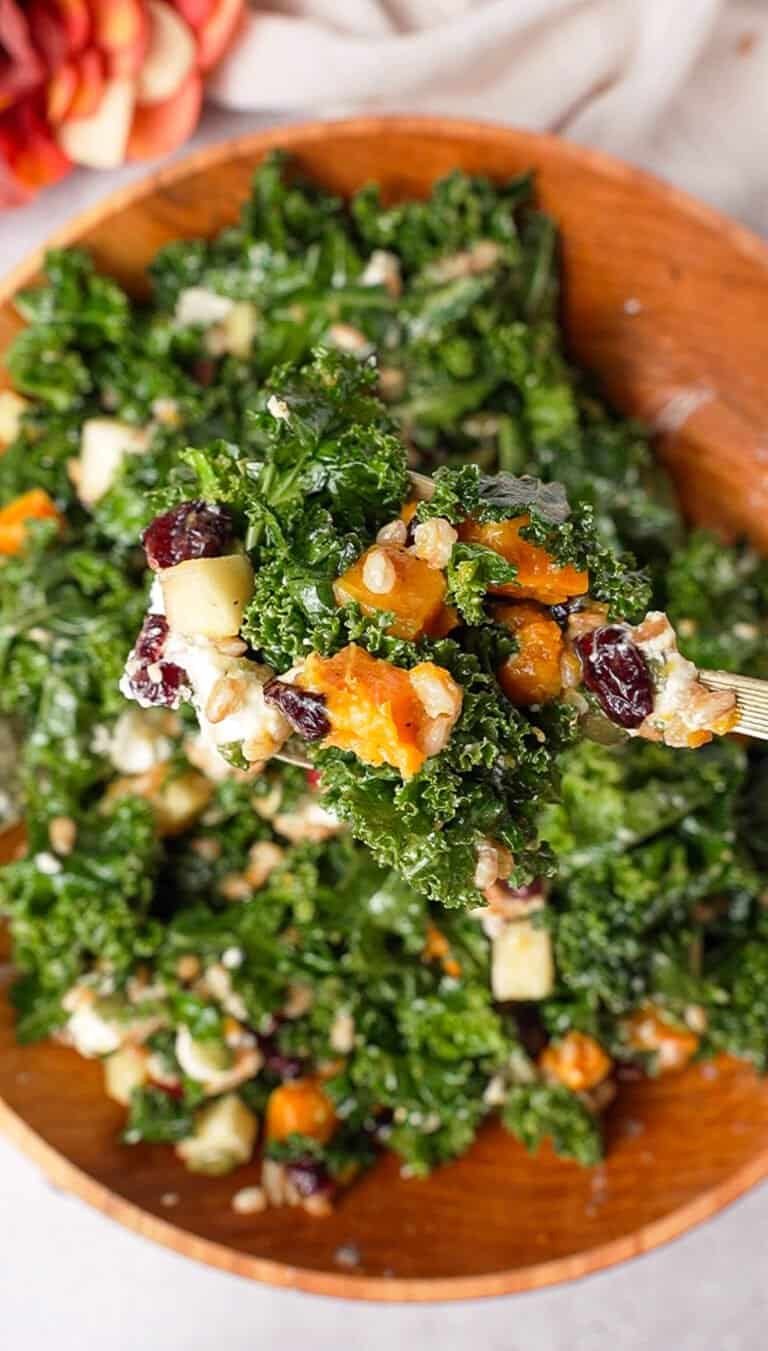 Fork lifting a bite of kale farro salad showing kale, farro, squash, and cranberries