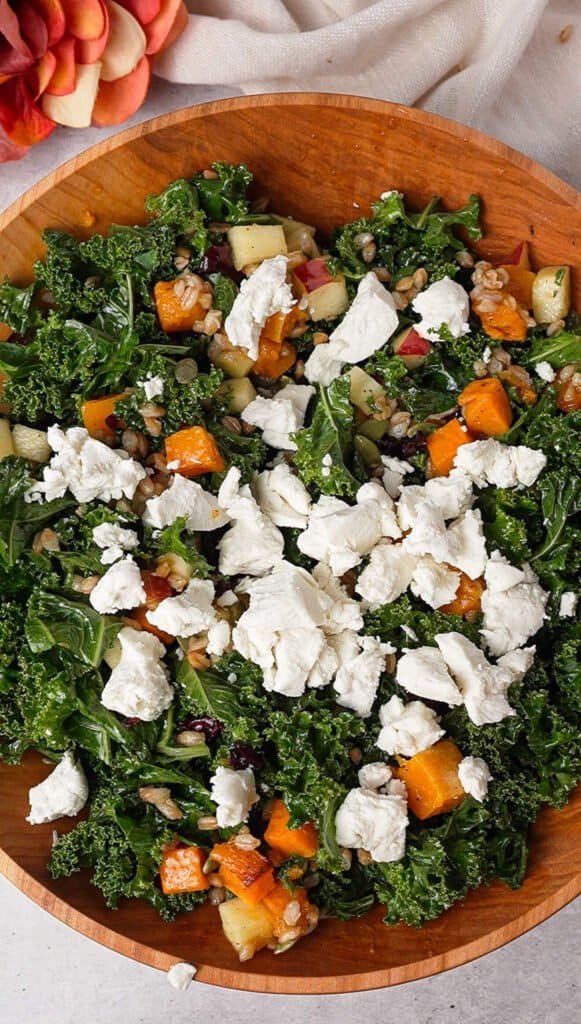 Kale farro salad topped with crumbled goat cheese, roasted squash, and dried cranberries
