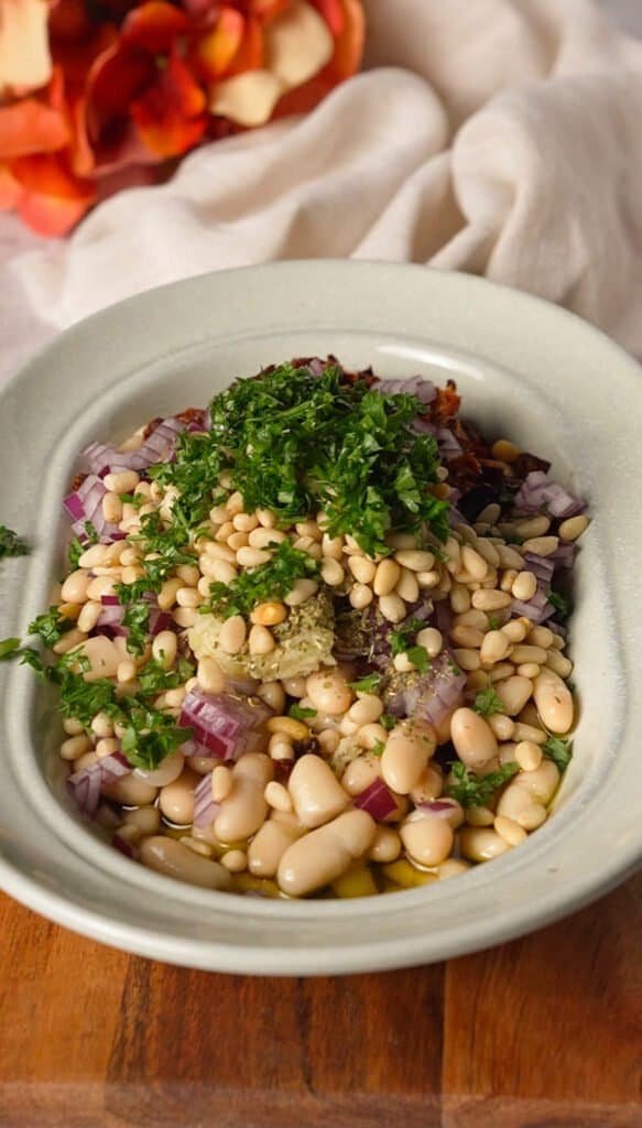 Marinated white bean dip ingredients layered in a bowl before mixing