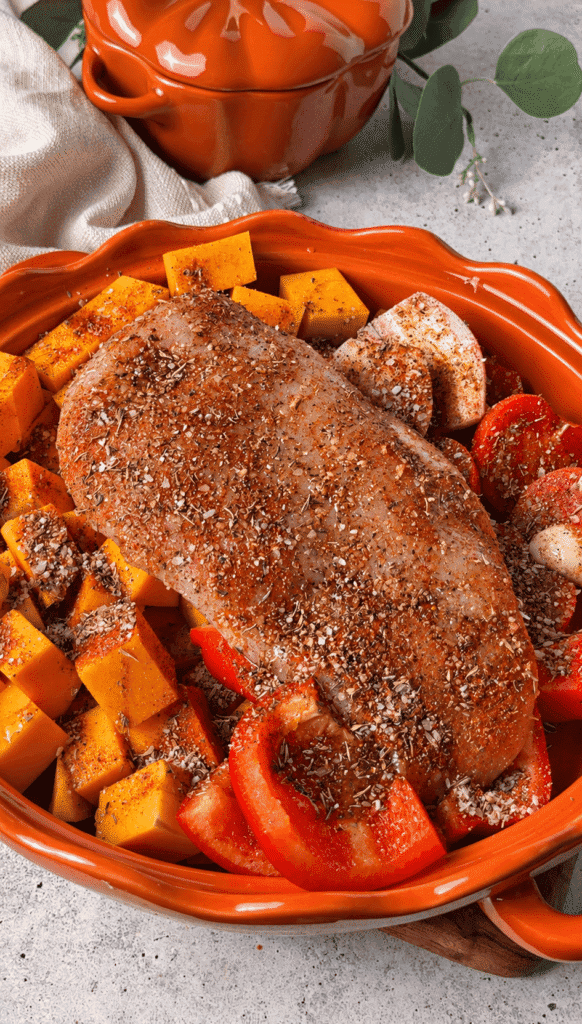 Seasoned chicken breast arranged with butternut squash, peppers, tomatoes and shallot before roasting